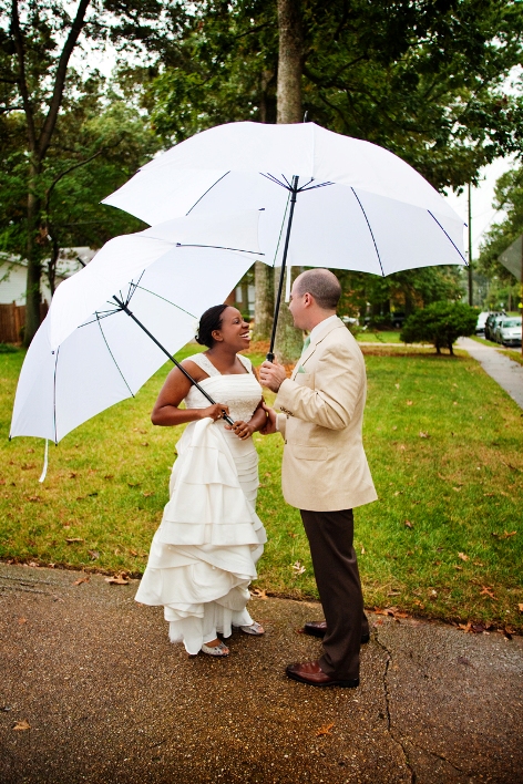 bride and groom meet under white umbrellas