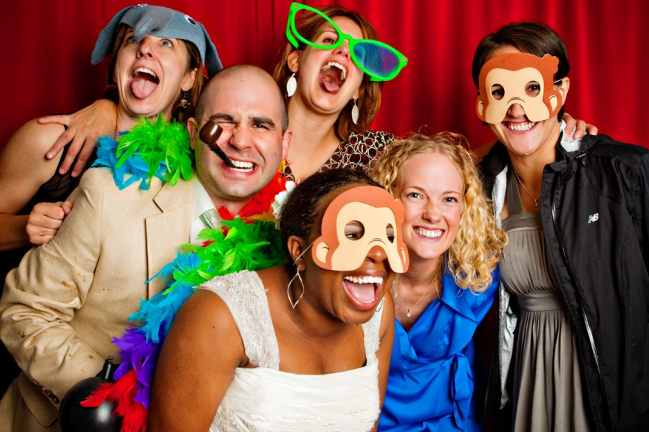 Bride, groom and friends use props in the photobooth