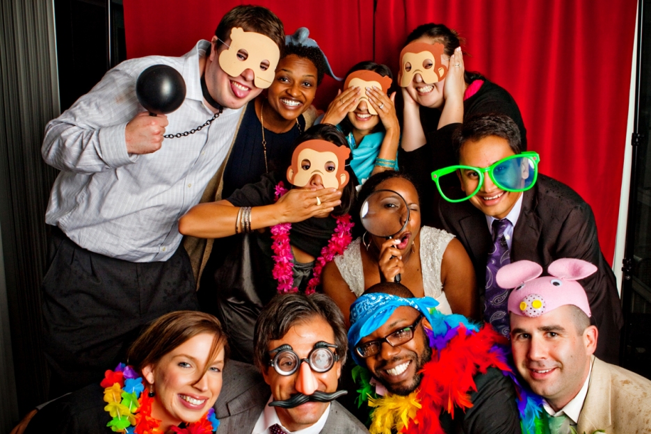 Bride, groom and friends use the props in the photo booth