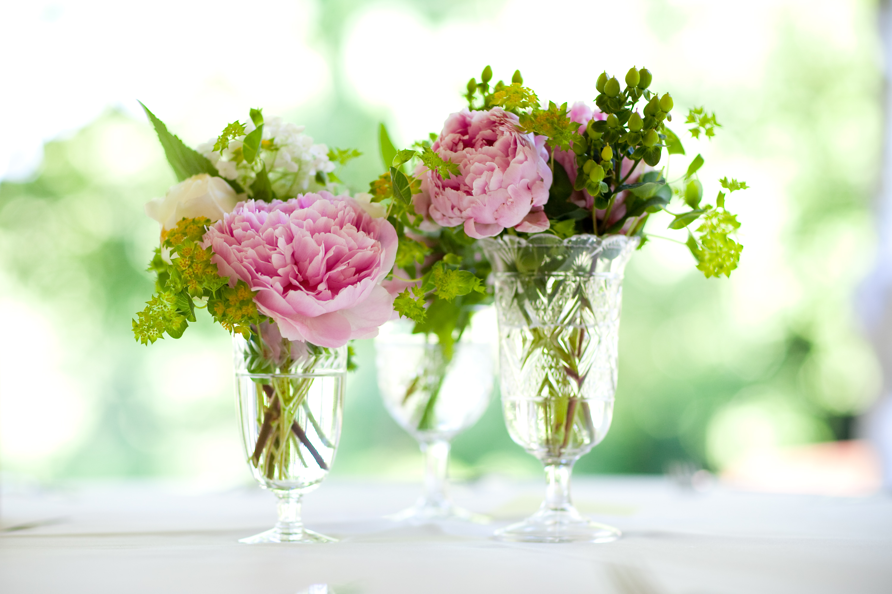 pink, green and white blooms in small cut-glass vessels