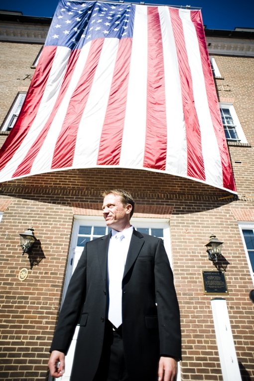 Groom stands in front of a huge American flag