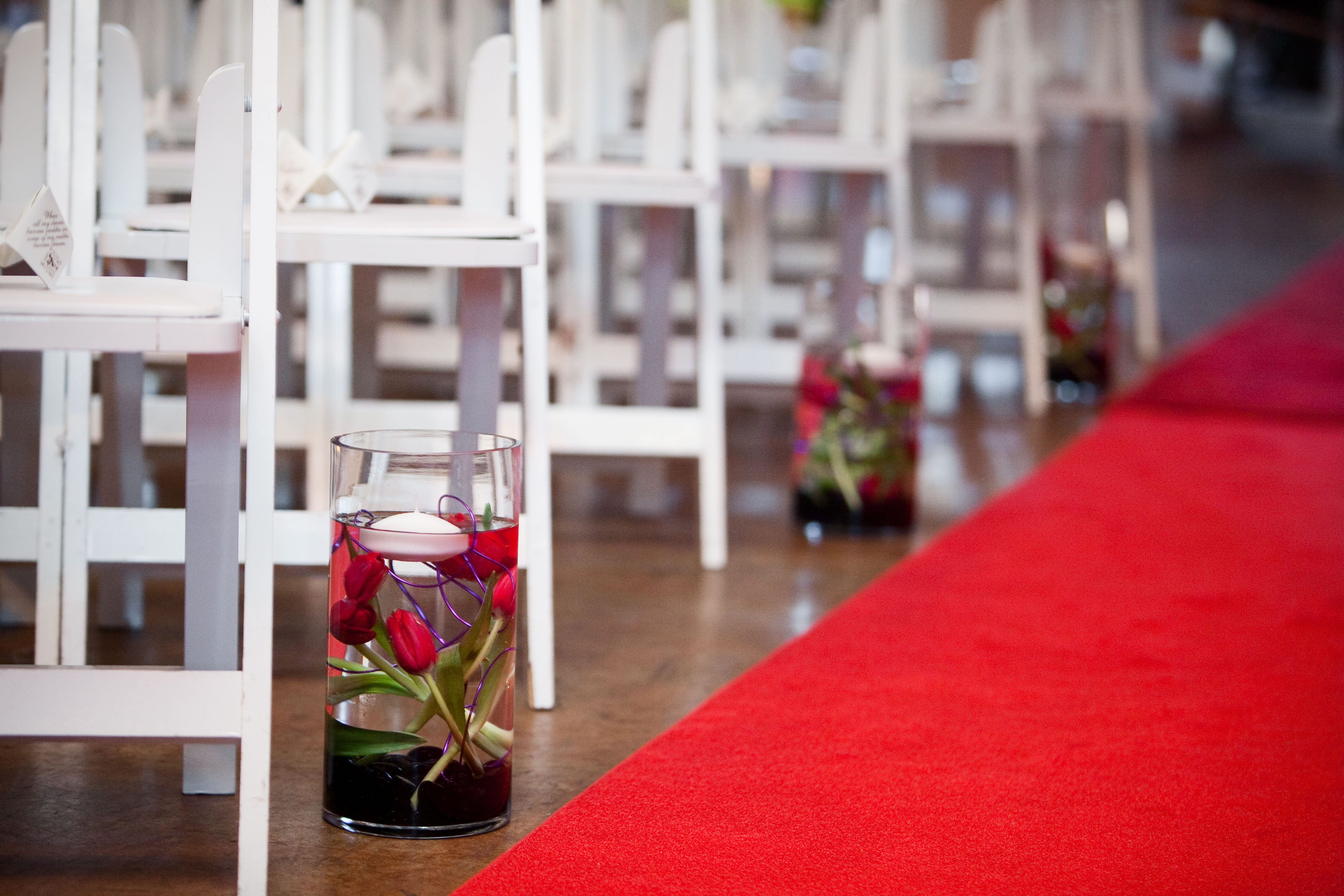 red carpet aisle runner lined with floral arrangements featuring submerged red parrot tulips