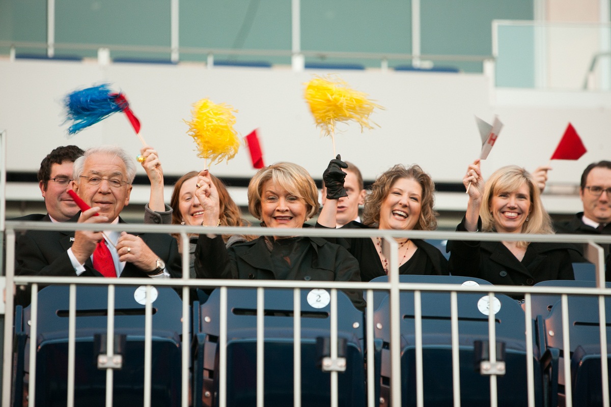 guests wave pom poms and pennant flags at the start of the ceremony