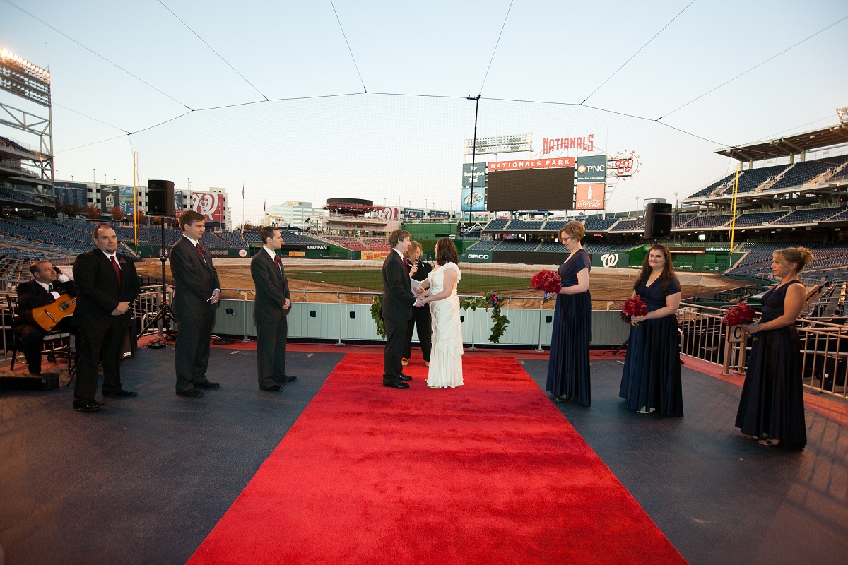 The bride and groom marry behind home plate at the end of a red carpet runner