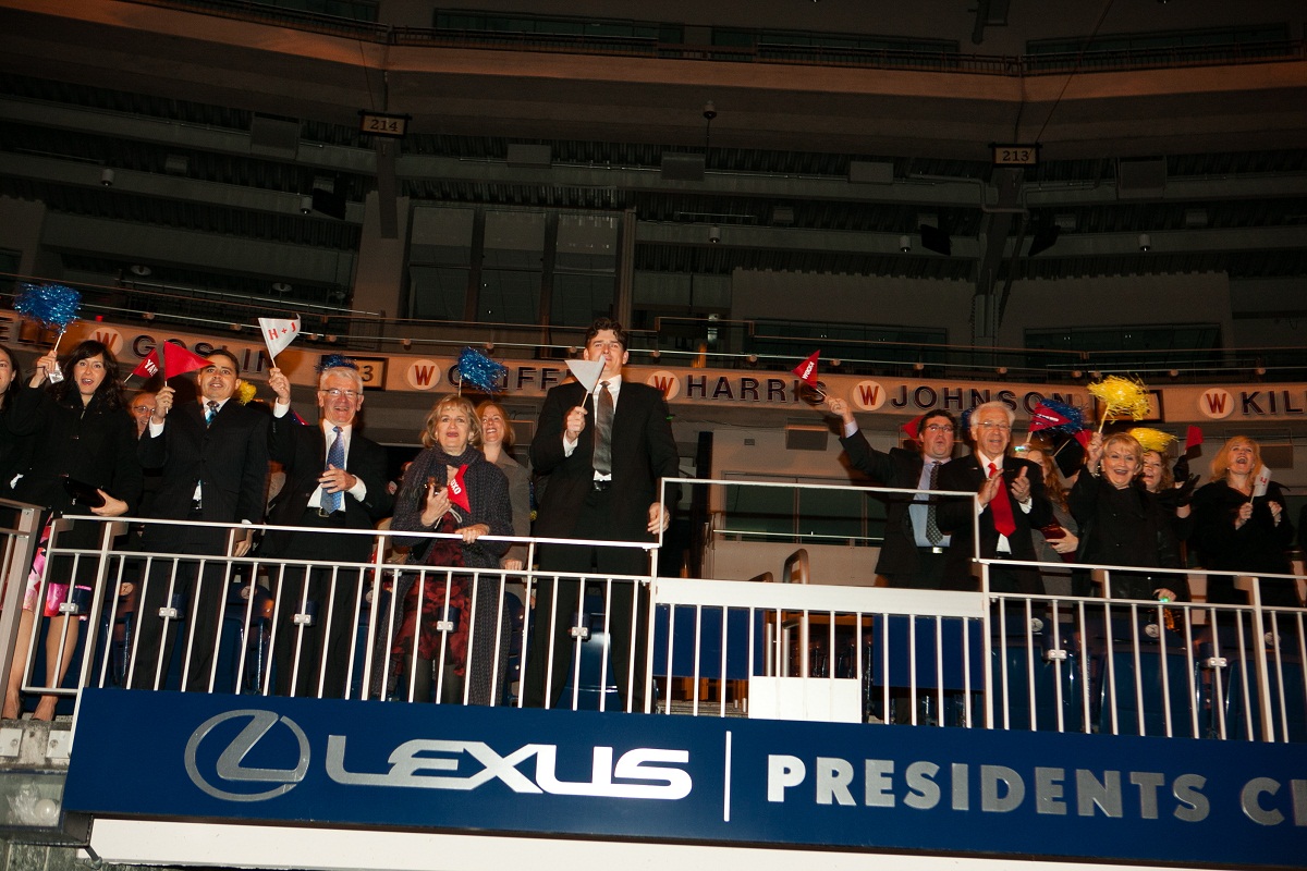 The guests cheer and wave pom poms and pennant flags from the stands at the end of the ceremony