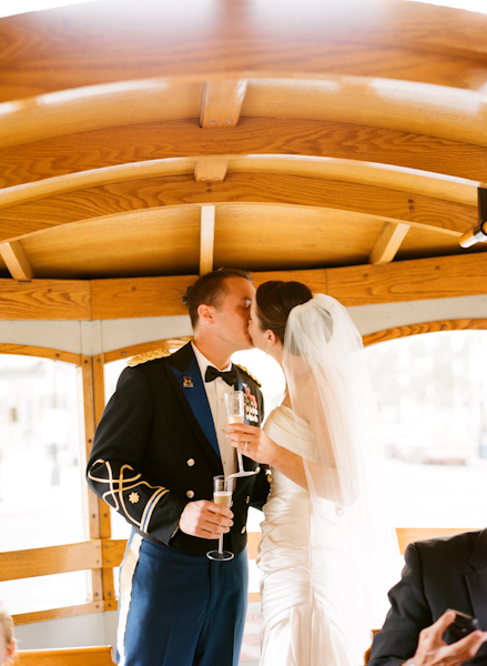 bride & groom hold flutes of champagne and kiss in the trolley
