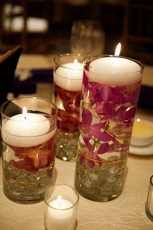 some dinner tables feature 3 vases with submerged orchids