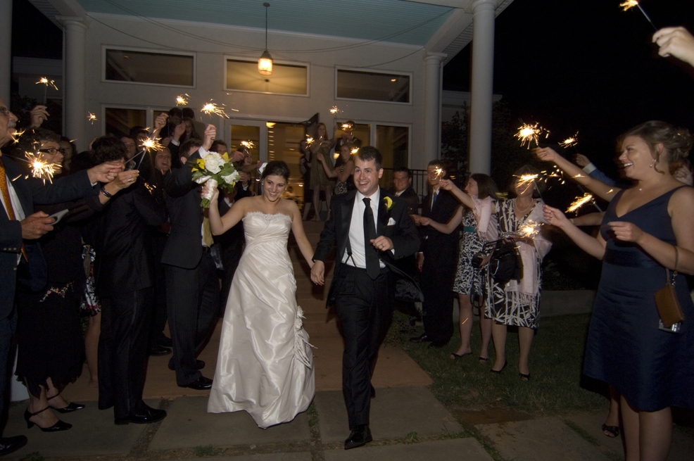 Bride and groom exit the wedding reception through a line of sparklers
