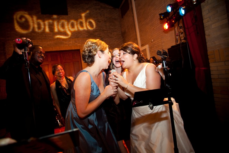 bride and bridesmaids sing on stage with the band