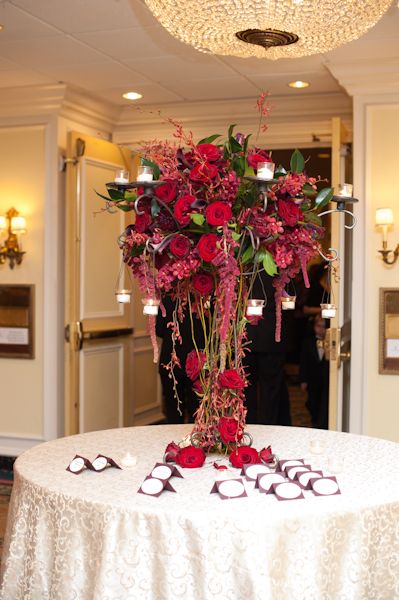 tall red, plum and eggplant floral arrangement on the escort card table
