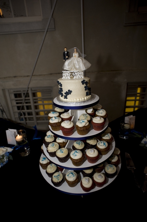 tiers of cupcakes with small round cake and vintage cake topper on top