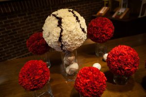 red carnation pomanders with a larger pomander designed to look like a baseball