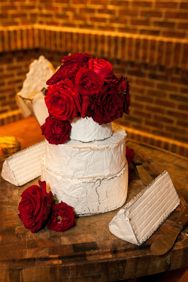 cheese wheels in the shape of a wedding cake with red roses