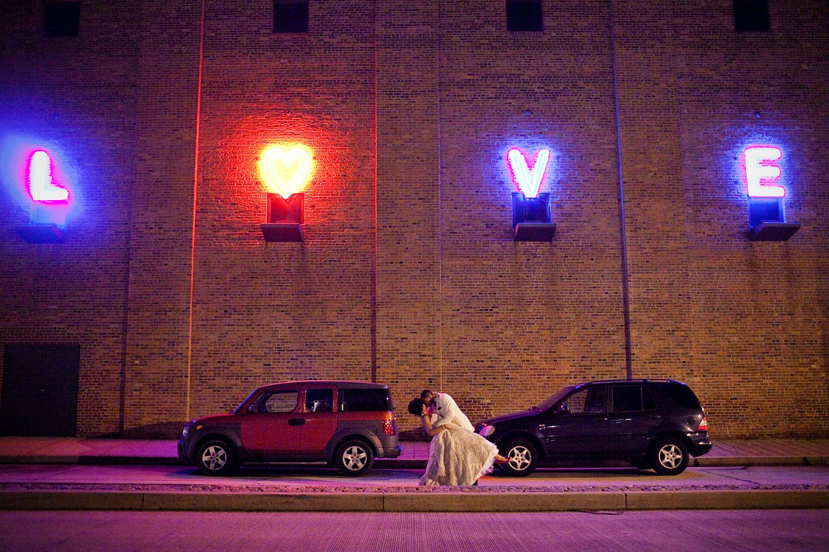bride and groom in front of the "LOVE" neon sign