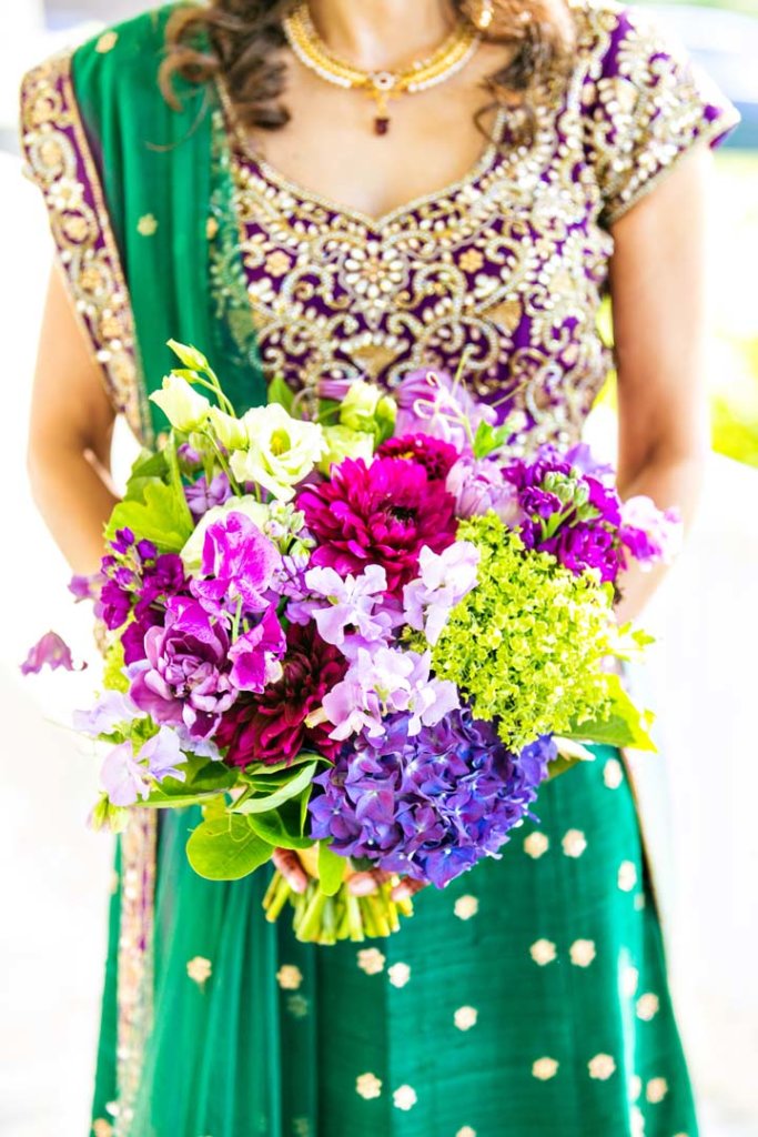 A colorful green and purple bridal bouquet to compliment the bride's green sari