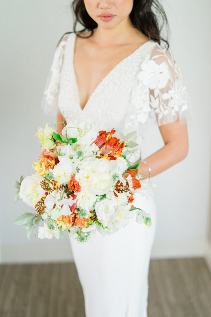 a white bridal bouquet with hot orange accents 