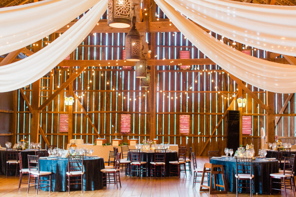 Riverside on the Potomac wedding reception  in the barn with ceiling drapery, dark wood chivari chairs, teal velvet linens, planned by Bellwether Events