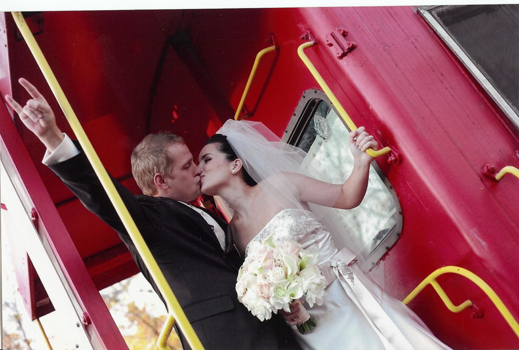 bride and groom on red train caboose - kissing