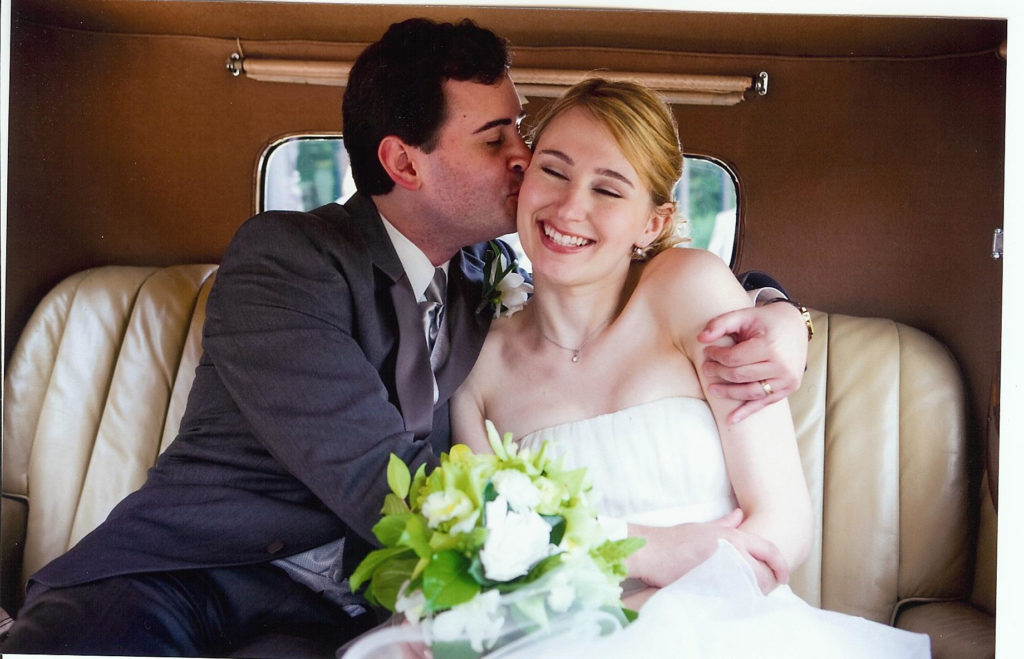 Bride and groom embrace in vintage car after their wedding ceremony