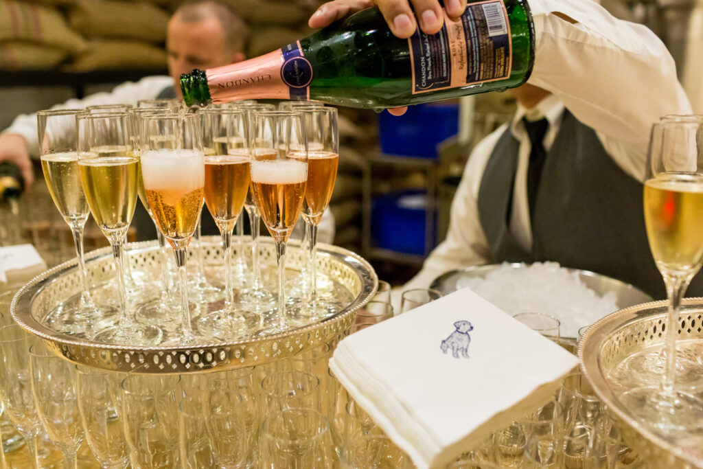 a bartender pours pink bubbly into champagne flutes