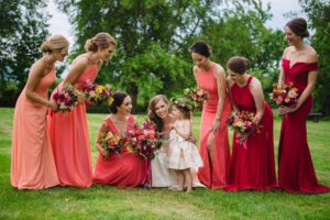 Bridesmaids in red, orange and coral dresses at a Virginia wedding planned by Bellwether Events