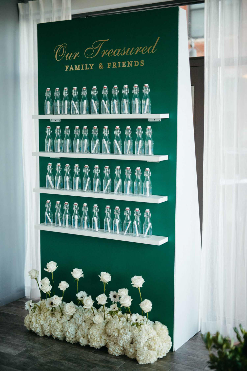 Creative wedding seating chart of glass bottles bottles on a green wall at Hummingbird Restaurant in Alexandria, Virginia, created by Bellwether Events Creative wedding seating chart of glass bottles bottles on a green wall at Hummingbird Restaurant in Alexandria, Virginia, created by Bellwether Events