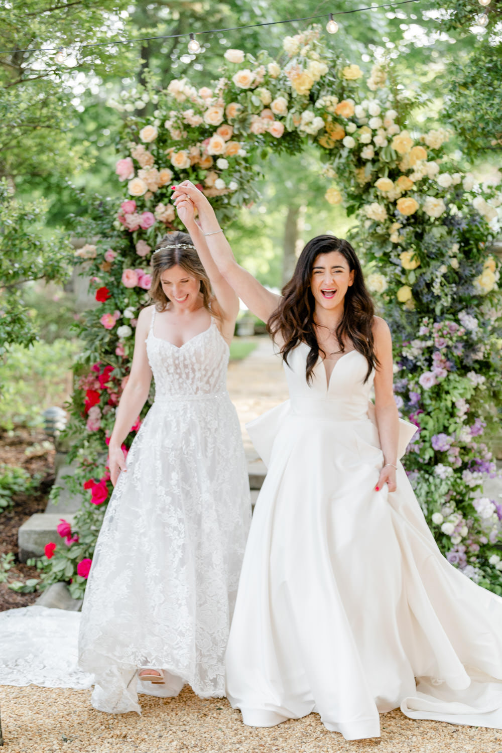 Two brides celebrating their wedding in front of a floral altar - wedding planned by DC's Bellwether Events Two brides celebrating their wedding in front of a floral altar - wedding planned by DC's Bellwether Events