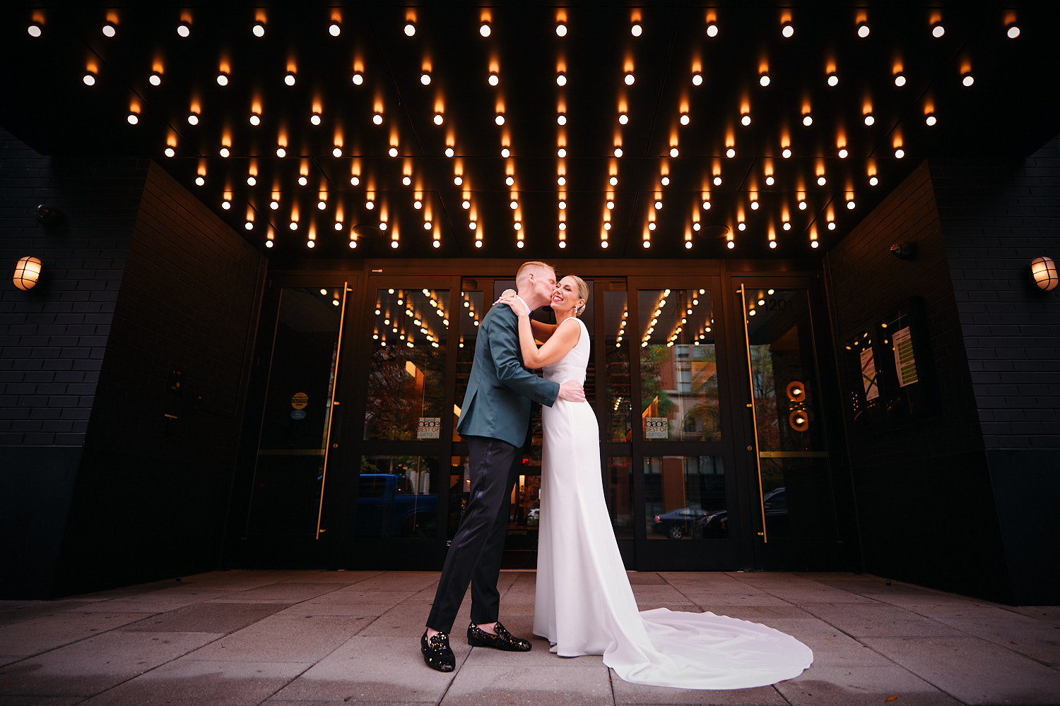 A happy bride and groom kissing under a theater marquee in Washington DC - wedding planned by Bellwether Events