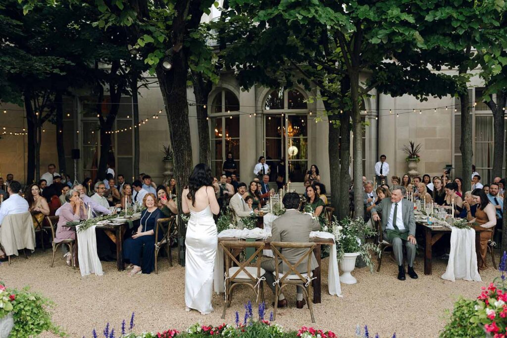 bride addresses her guests at their al fresco long wedding tables in Linden Grove at Meridian House